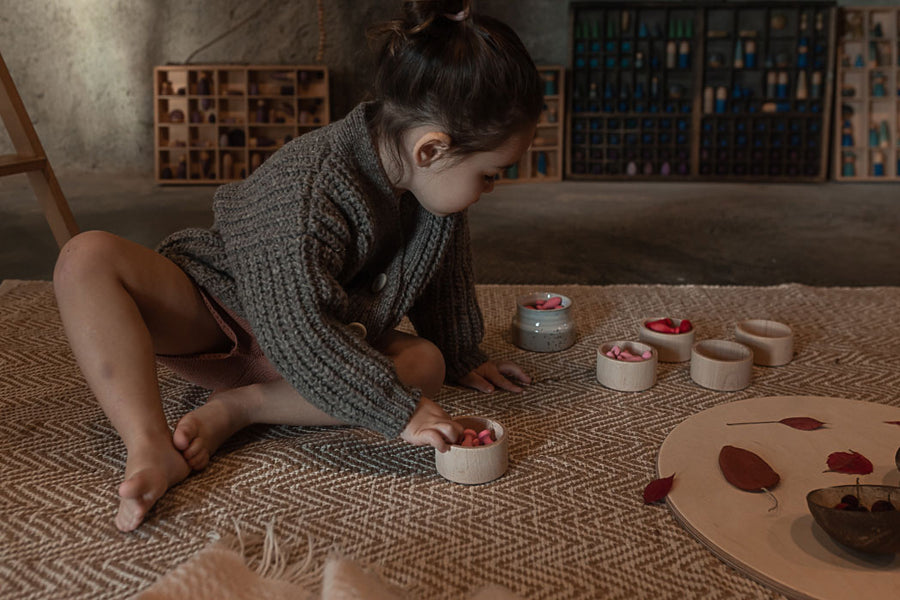 Girl playing on the floor with 6 small grey pots