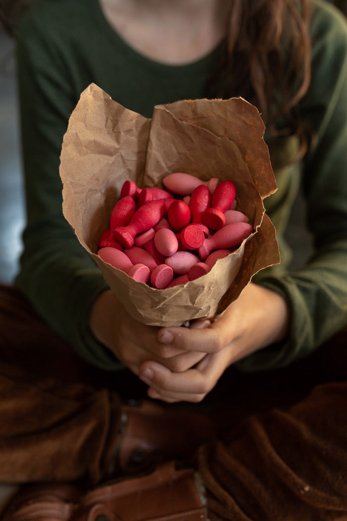 Girl holding a brown paper cone filled with Grapat Mandala Flower Petals to resemble a bunch of flowers.