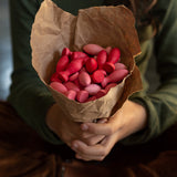 Girl holding a brown paper cone filled with Grapat Mandala Flower Petals to resemble a bunch of flowers.