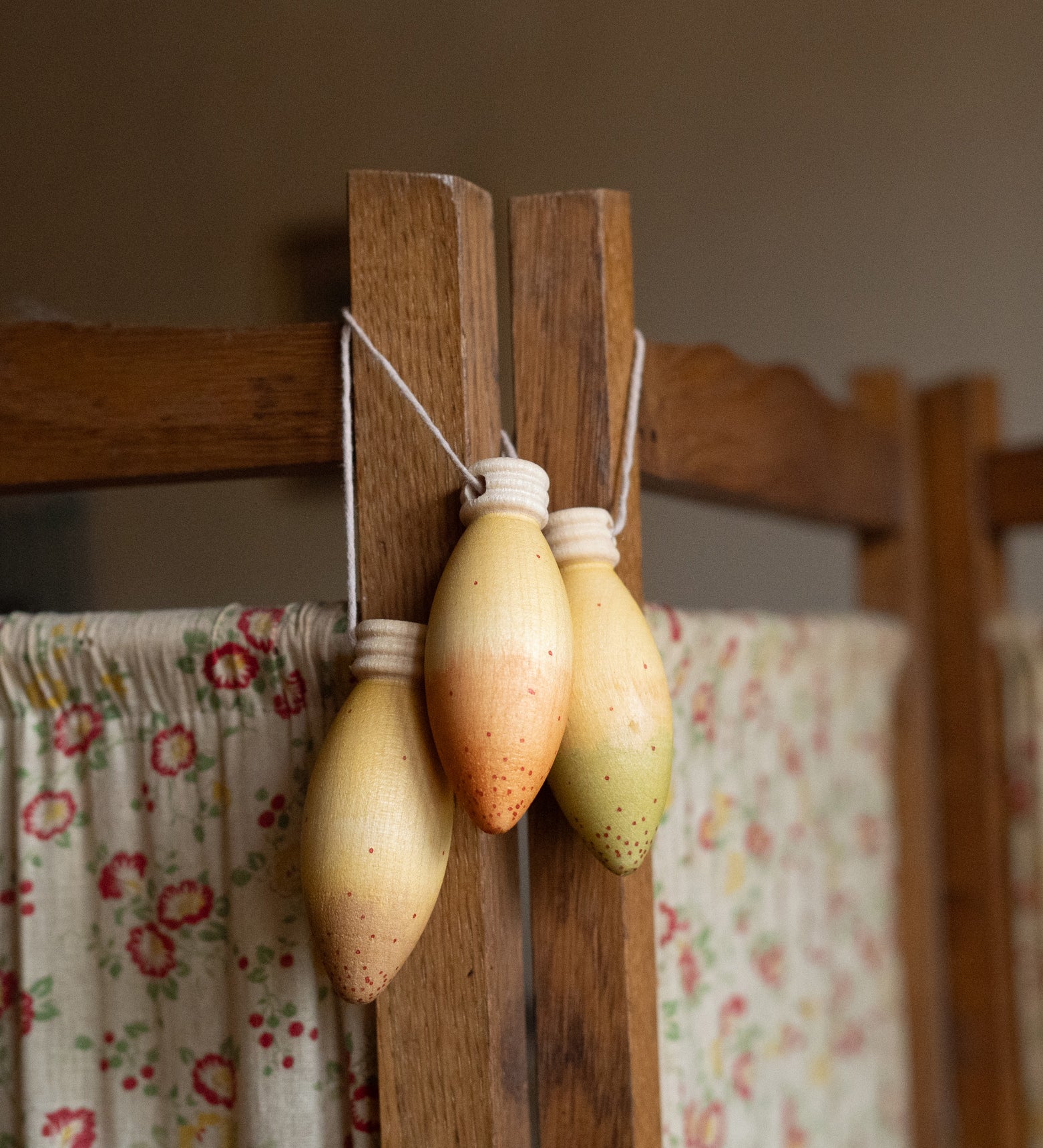 light purple, orange and green wooden Grapat glow lamps hanging on a wooden frame