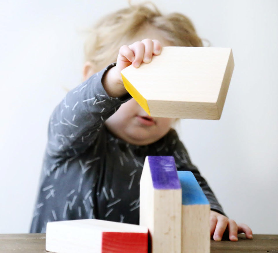 Grapat Six Wooden Houses Set in play with toddler stacking. Different simple geometric shapes in natural wood and colourful painted roofs. White background.