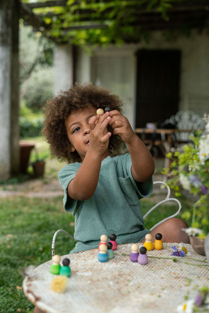 Close up of young child holding up some Grapat baby wooden peg doll toys