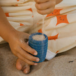 A child is playing with the yellow vase and orange pot from the Grapat Wooden Rainbow Sorting Pots