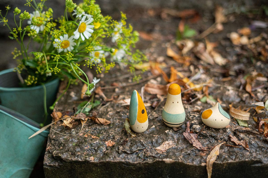 Grapat eco-friendly handmade hooray figures stood on a wet rock next to a pot full of white flowers