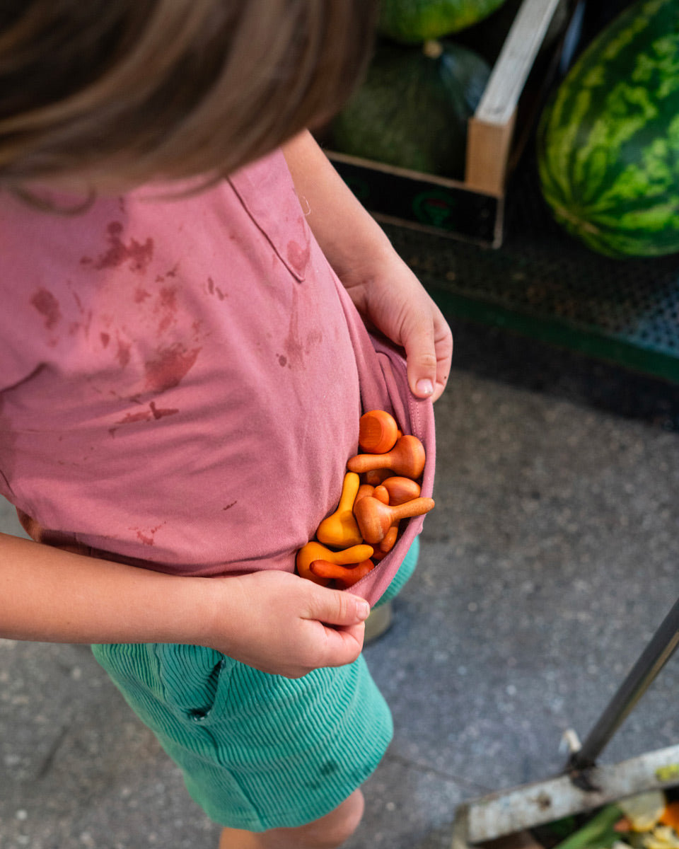 Close up of child cupping some Grapat handmade wooden mandala pumpkins in their t-shirt