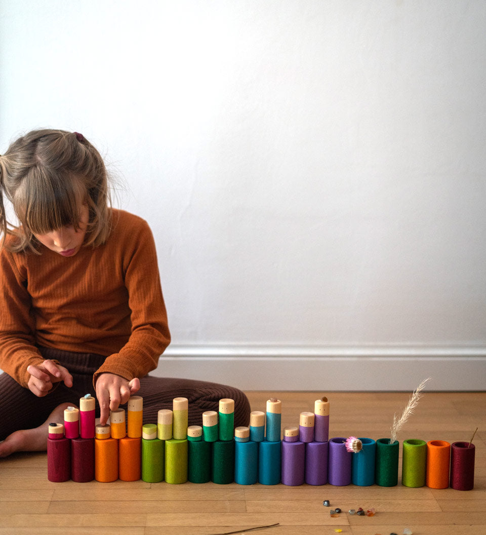 Child sat on the floor playing with the Grapat plastic-free stacking wooden La toy set