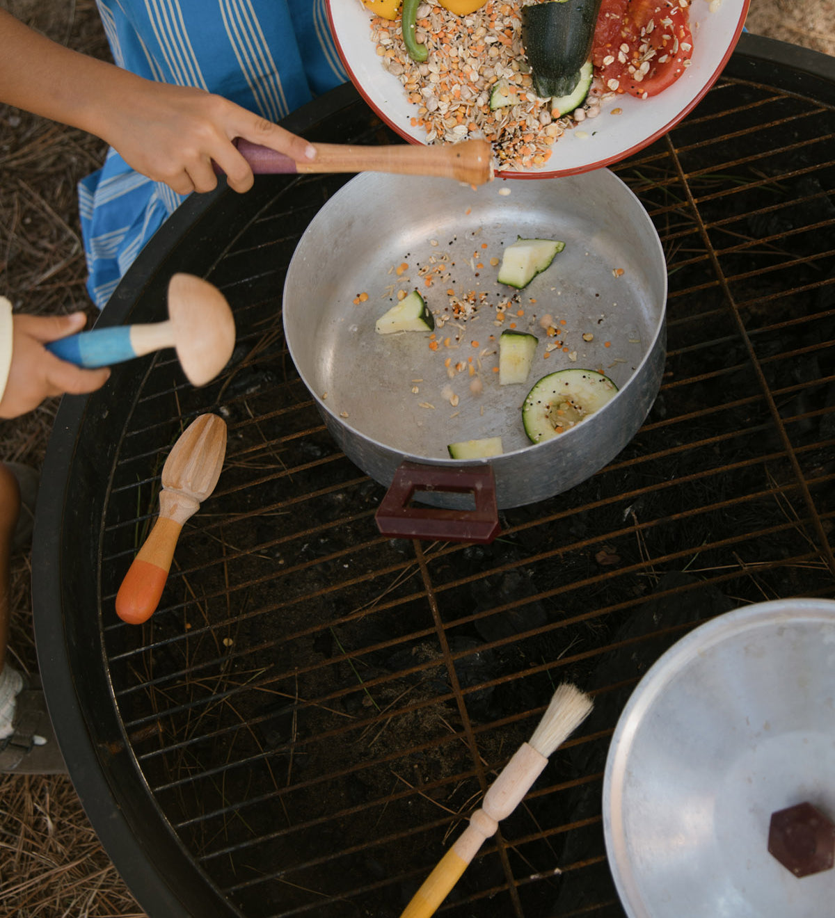 Children are using the Grapat Wooden Sensory Play Tools to make a meal. One child is pouring in lentils