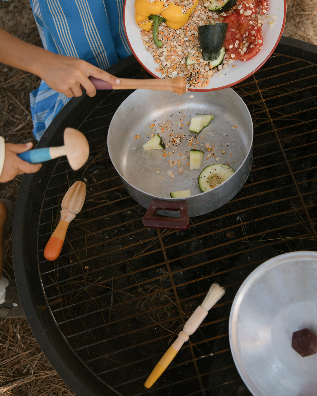 Children are using the Grapat Wooden Sensory Play Tools to make a meal. One child is pouring in lentils