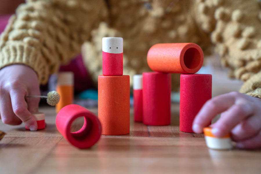 Close up of child's hands stacking the Grapat wooden Lo toy set on a wooden floor