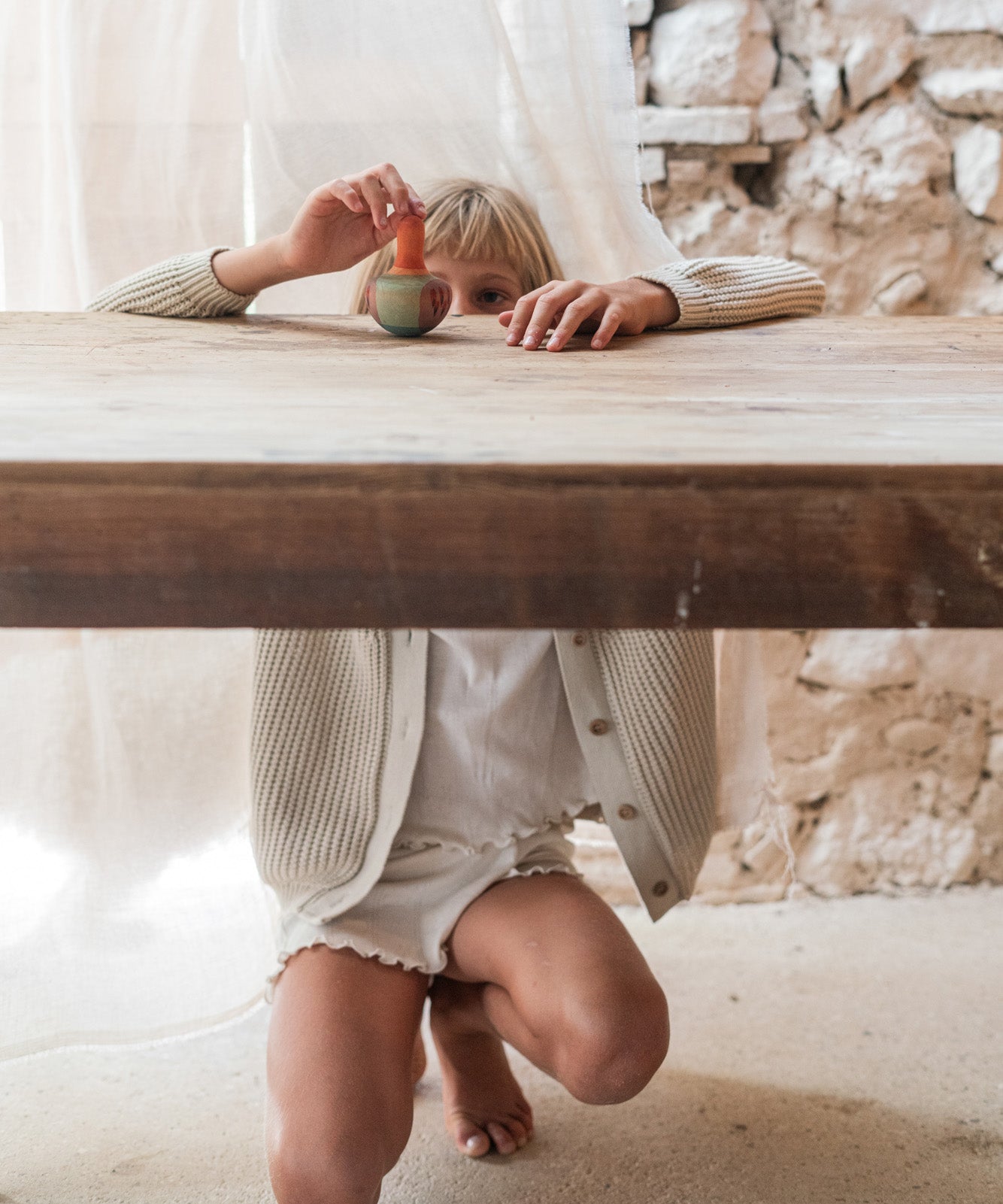 A child playing with the Grapat wooden mellow orange bird on a wooden table