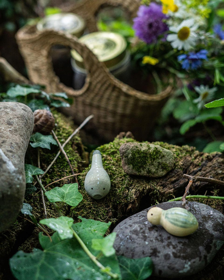 Close up of the Grapat eco-friendly small wooden wild toy set on a log in front of a basket full of flowers