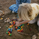 Two children on the beach playing with various Grapat mandala pieces