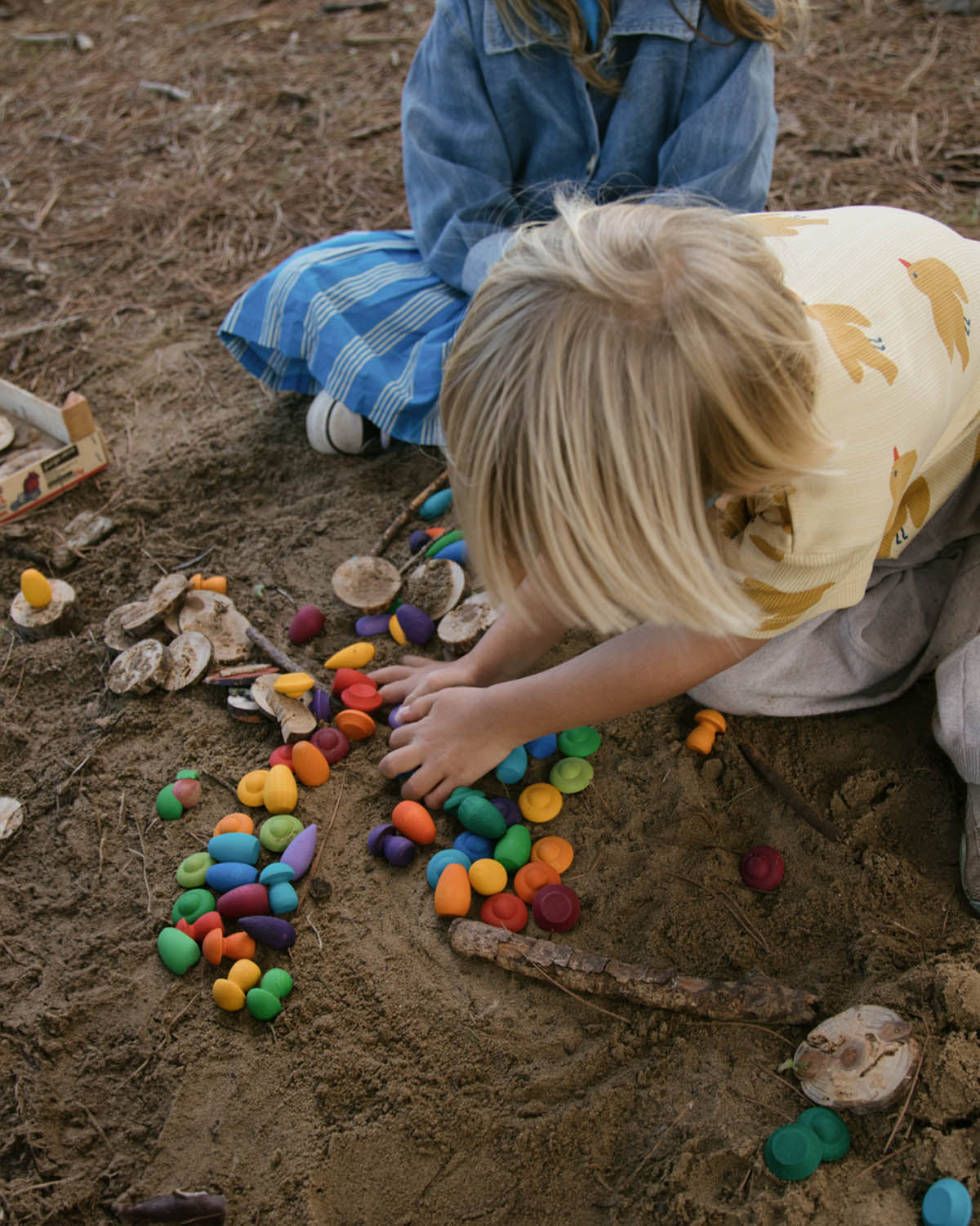 Two children on the beach playing with various Grapat mandala pieces