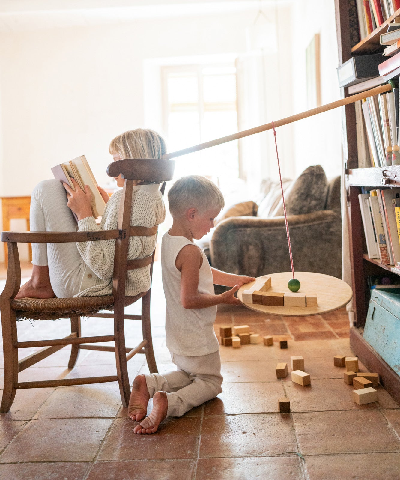 A child playing with the Grapat wooden pendulum set with wooden blocks on the floor