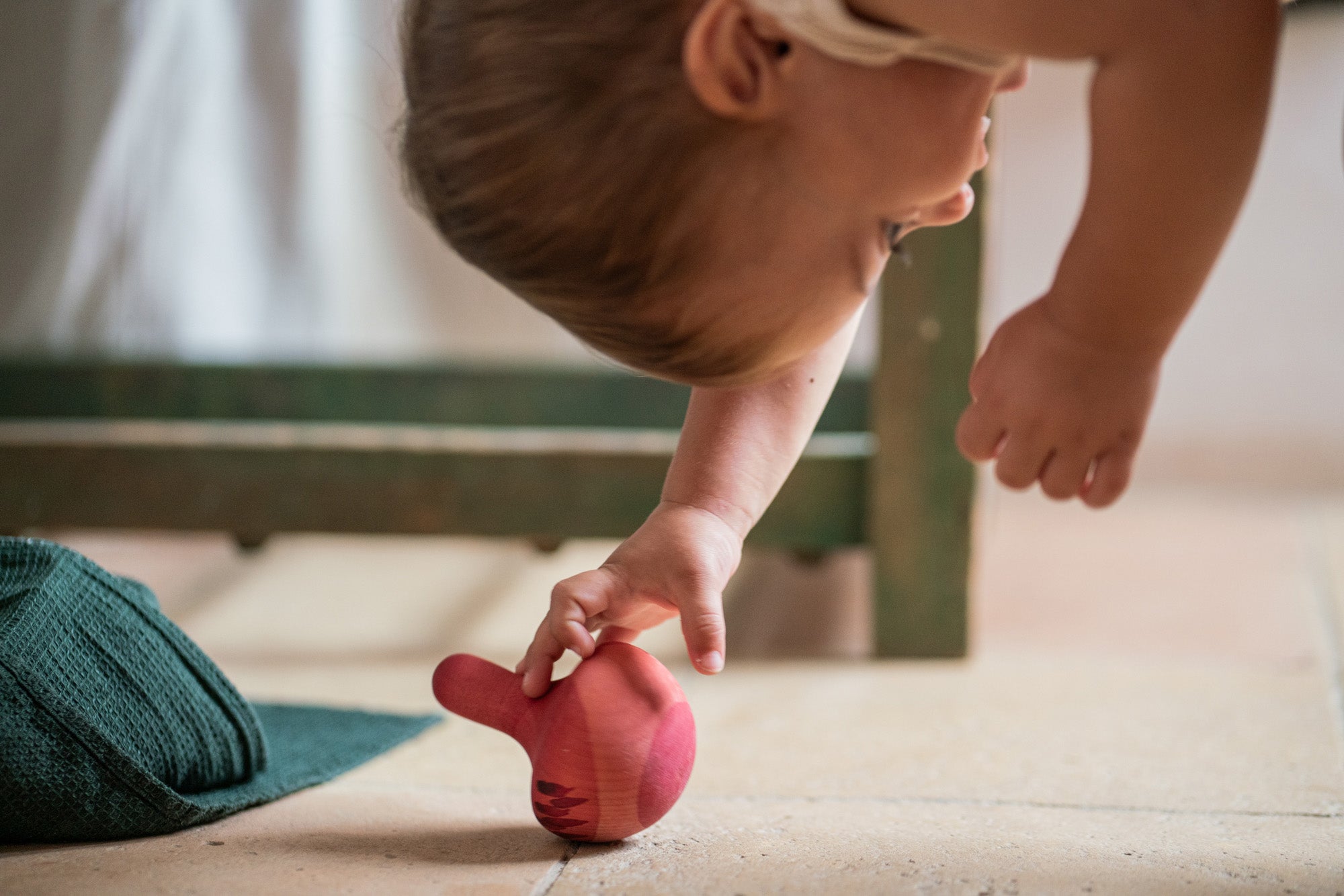 A child playing with the Grapat wooden pink chill bird on the floor