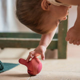 A child playing with the Grapat wooden pink chill bird on the floor