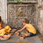 Child weaving some string into the thread of the Grapat handmade weaving frame toy