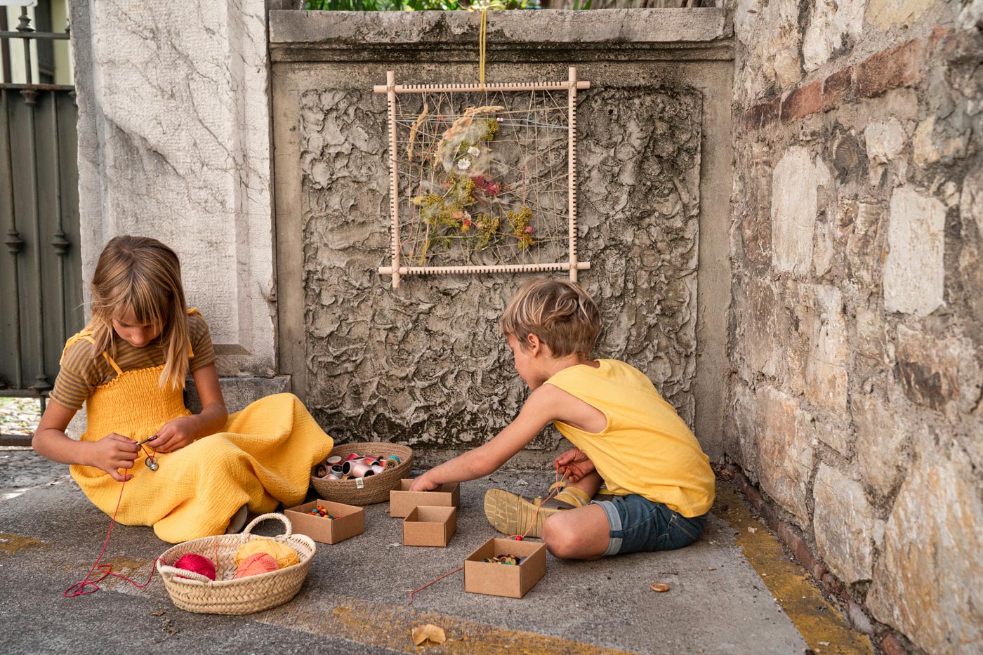 Child weaving some string into the thread of the Grapat handmade weaving frame toy