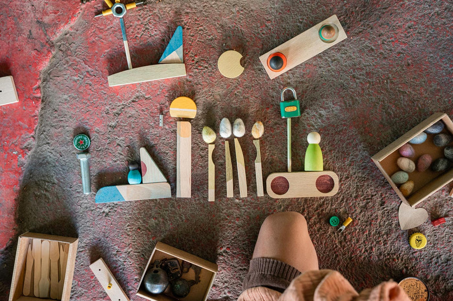 Close up of pieces from the Grapat happy place Waldorf toy set lined up of a stone floor