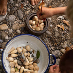 Close up of children playing with the Grapat eco-friendly natural wood mandala pieces in a white bowl on some small pebbles