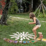 Young girl playing with grapat mandala pieces and the wooden petal platforms on some grass