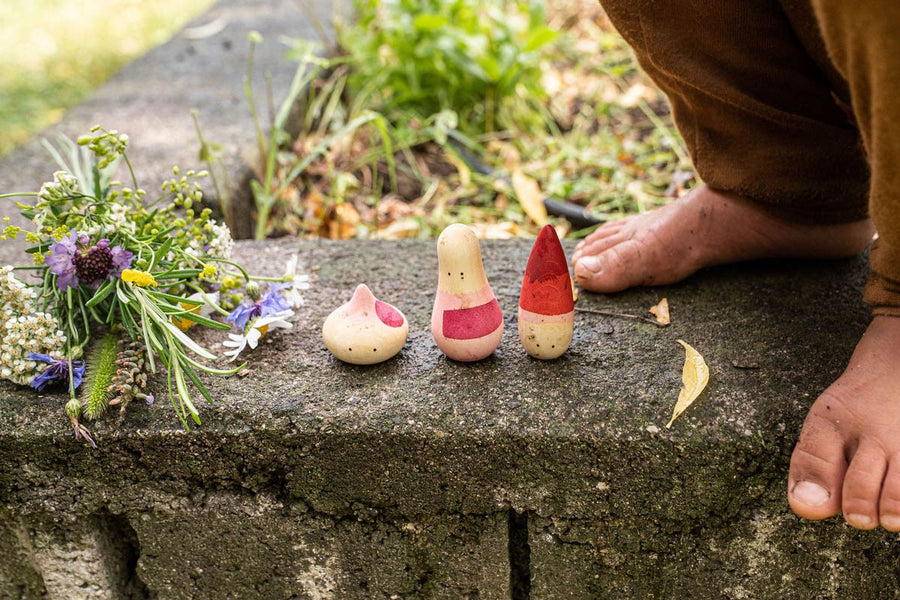 Close up of the Grapat yay wooden toy set on a stone wall next to a childs feet