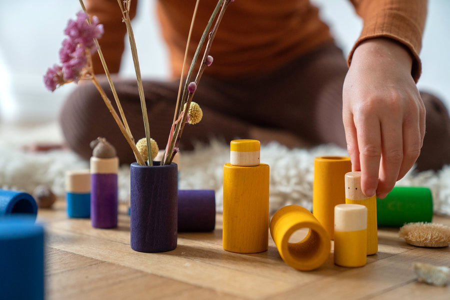 Close up of child's hands playing with the Grapat wooden Lo toy set on a wooden floor