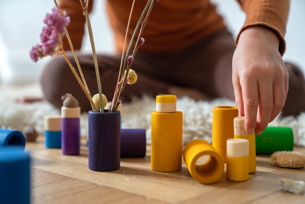 Close up of child's hands playing with the Grapat wooden Lo toy set on a wooden floor