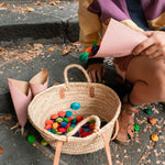 Close up of child sat on a step pouring Grapat Waldorf mandala flowers into a basket