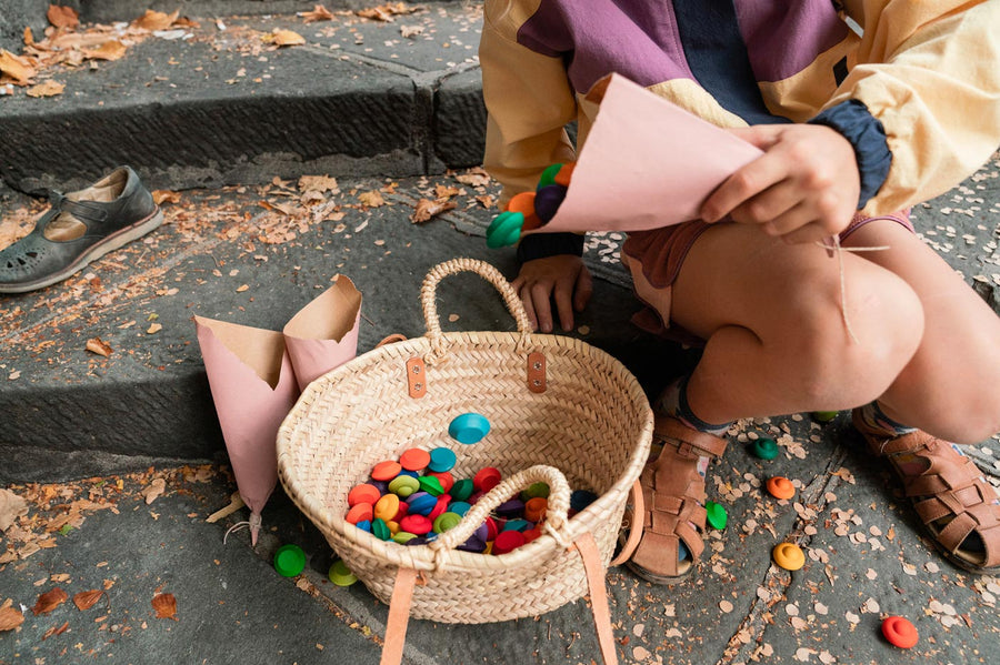 Close up of child sat on a step pouring Grapat Waldorf mandala flowers into a basket