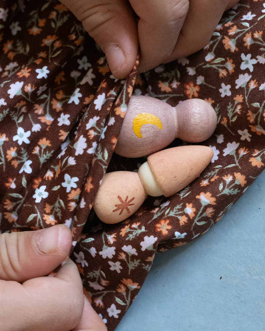 Two wooden Nin figures being held in two hands from the Grapat Moonlight Tale Play Set