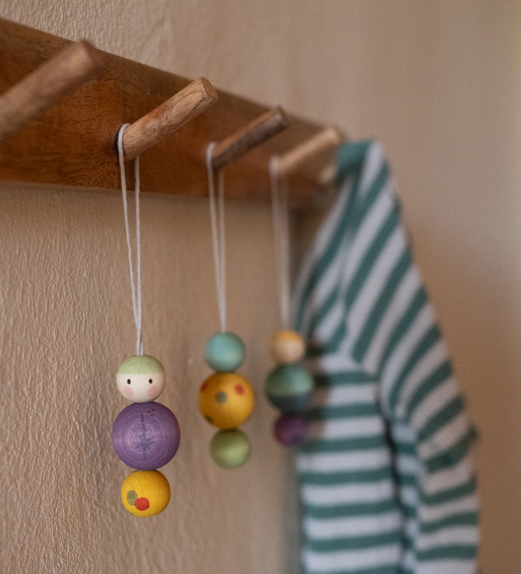 A wooden snow buddy wooden Grapat decoration hanging on a wooden hook.