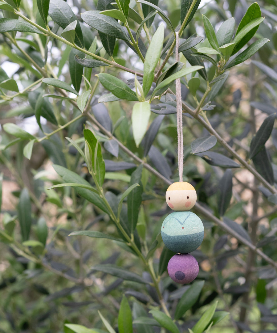 A purple and blue snow buddy wooden Grapat decoration handing on a tree