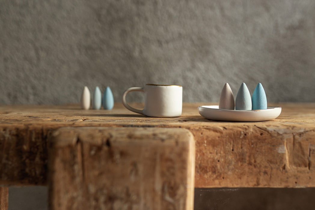 6 Grapat Mandala Snowflakes placed on a wooden table next to a white mug.