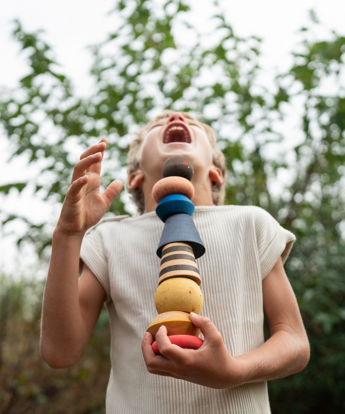 A child holding with the Grapat serendipity wooden stacking set outside 