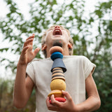 A child holding with the Grapat serendipity wooden stacking set outside 