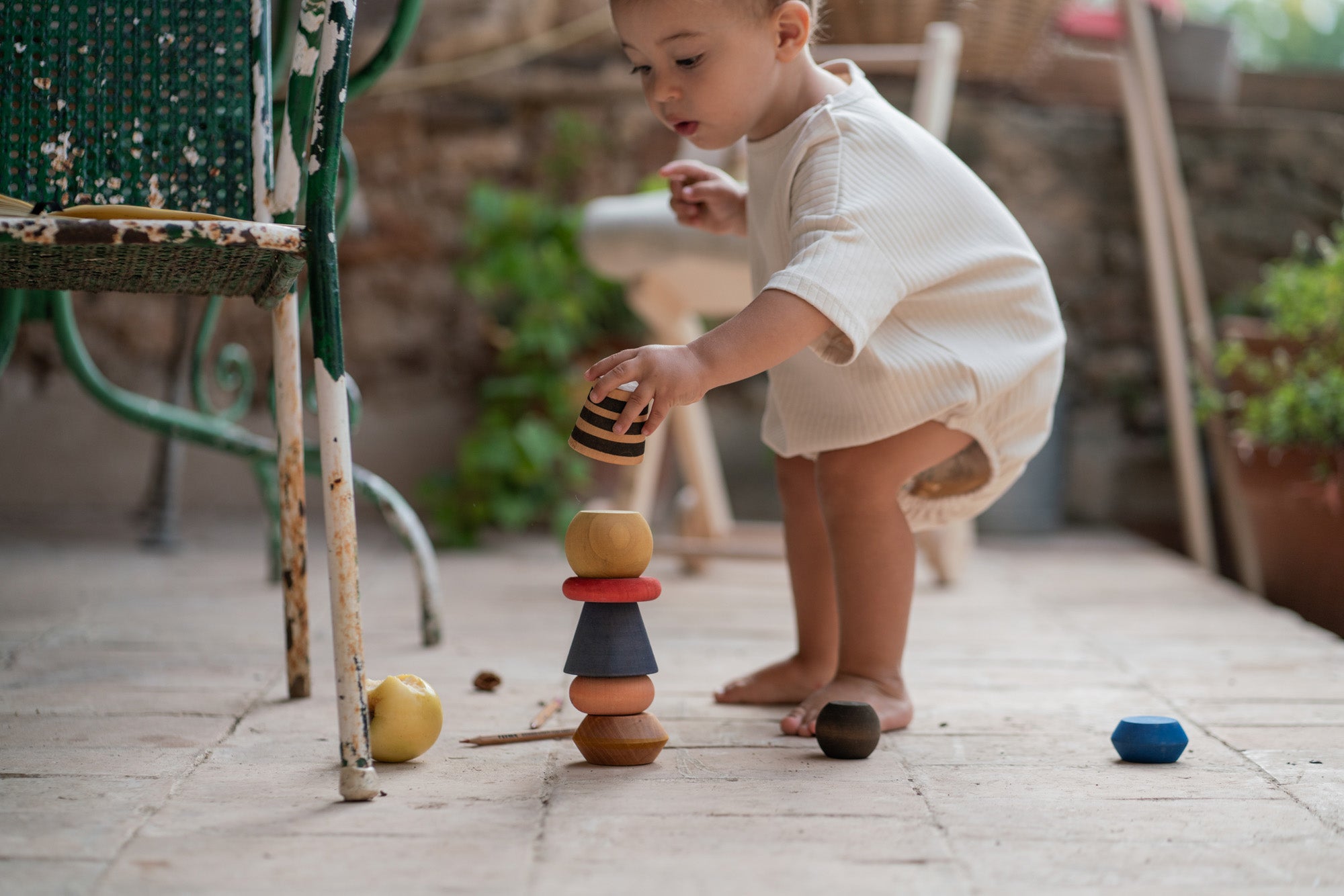 A child playing with the Grapat serendipity stacking set outside on the floor