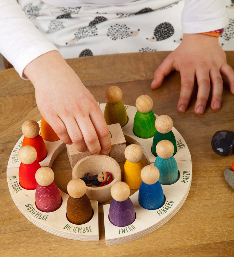 Grapat English Perpetual Calendar displaying the 12 nin peg dolls in colours representing the months of the year according to Waldorf teachings. The display ring has each month written in English around the edge and two cubes in the centre to mark the day