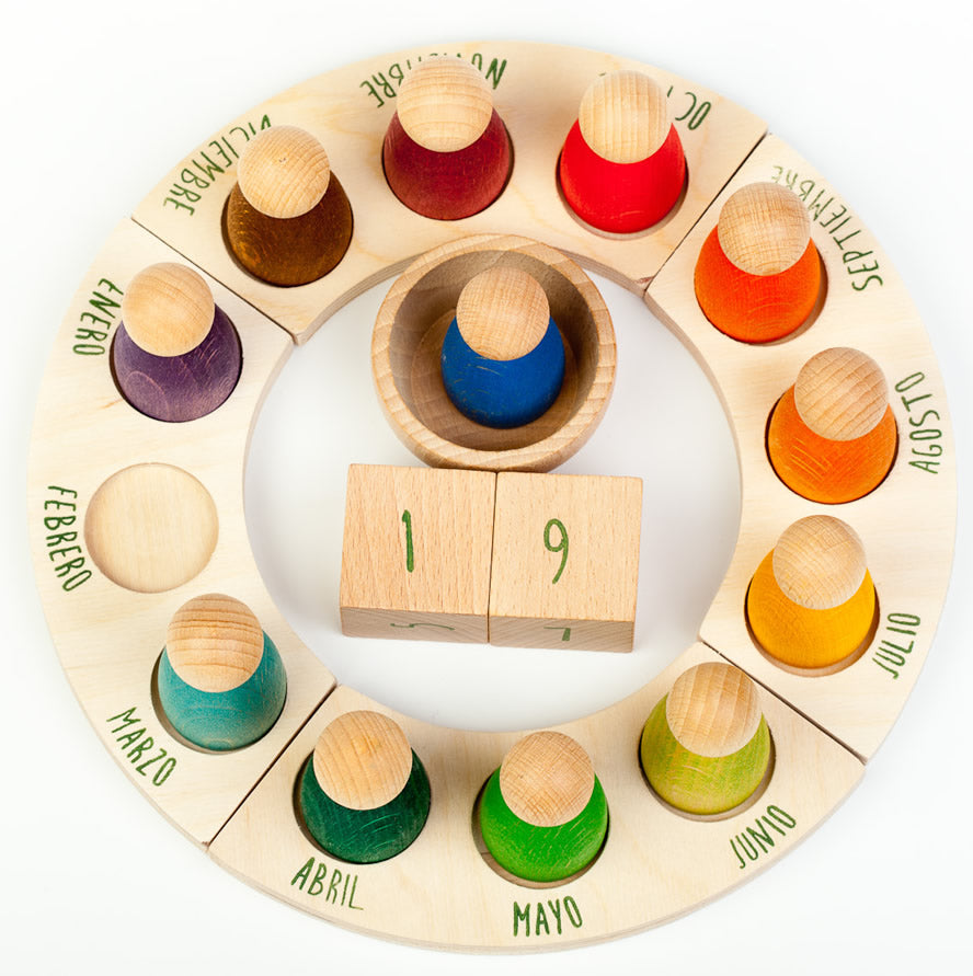 Grapat English Perpetual Calendar displaying the 12 nin peg dolls in colours representing the months of the year according to Waldorf teachings. The display ring has each month written in English around the edge and two cubes in the centre to mark the day