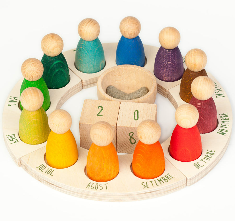 Grapat English Perpetual Calendar displaying the 12 nin peg dolls in colours representing the months of the year according to Waldorf teachings. The display ring has each month written in English around the edge and two cubes in the centre to mark the day