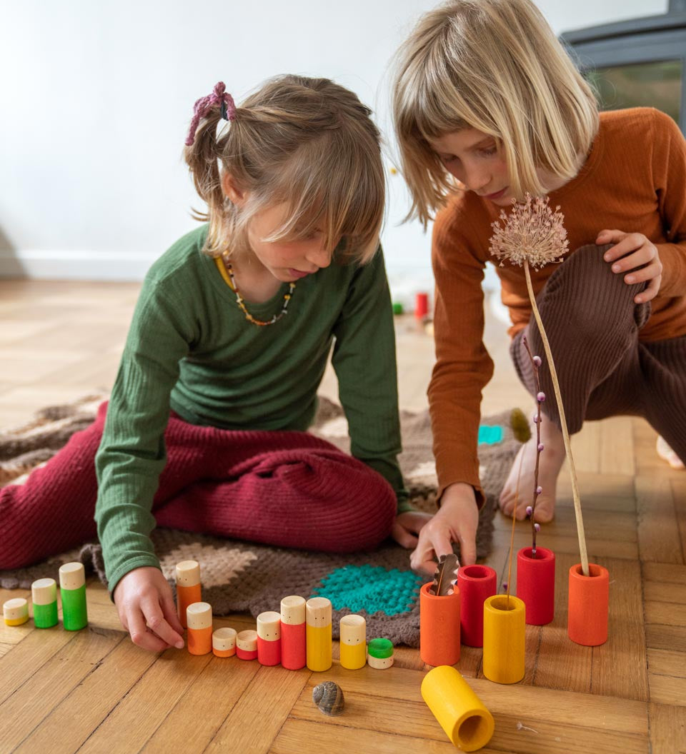 Two children playing with the Grapat plastic-free wooden lo tube set on a wooden floor