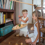 2 children playing with the Grapat wooden pendulum set on the floor