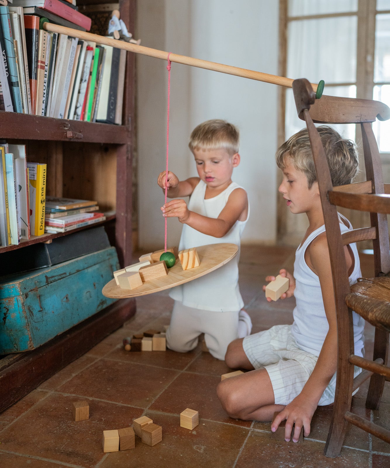 2 children playing with the Grapat wooden pendulum set on the floor