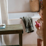 A child playing with the Grapat wooden pink chill bird next to a  table