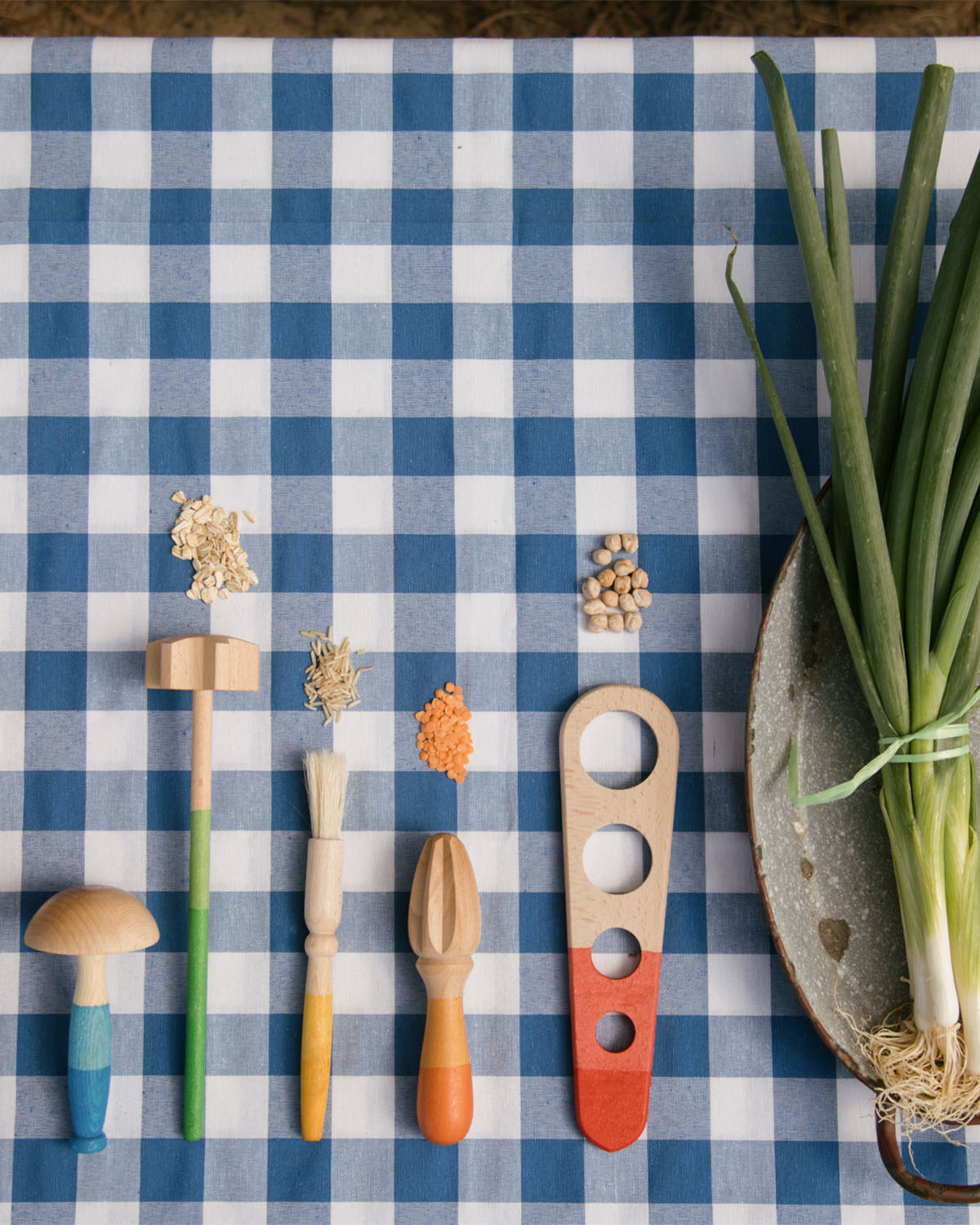 A child is mixing different food items together with the blue and purple handled Grapat Wooden Sensory Play Tools