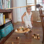 A child playing with the Grapat wooden pendulum set with wooden blocks on the pendulum and the floor