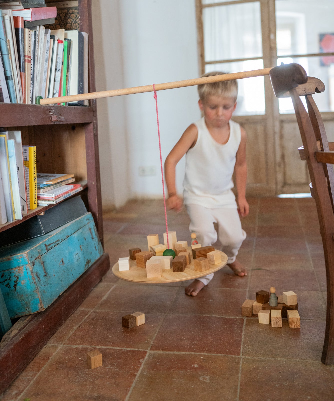 A child playing with the Grapat wooden pendulum set with wooden blocks on the pendulum and the floor