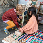 2 children crouched down reaching into the Grapat wooden permanence toy box