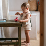 A child playing with the Grapat wooden pink chill bird on a wooden table