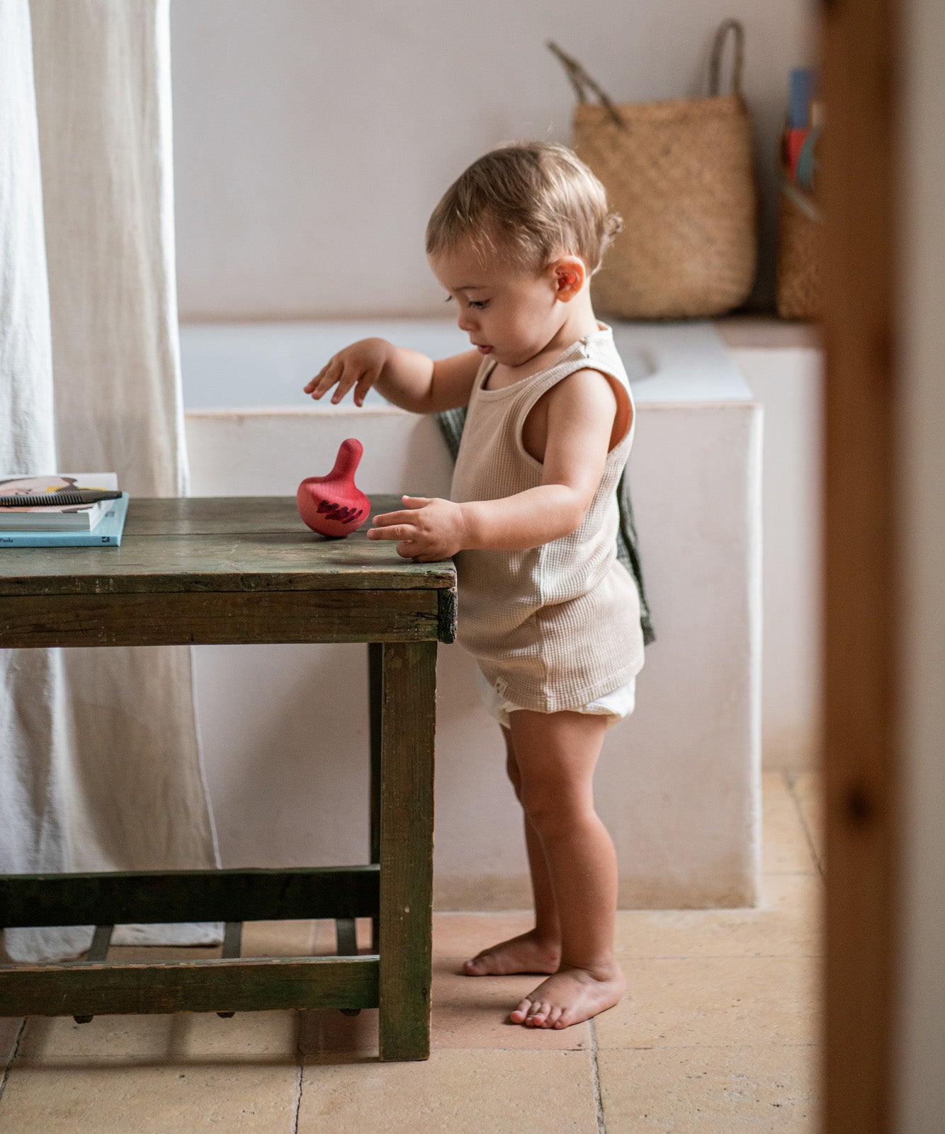 A child playing with the Grapat wooden pink chill bird on a wooden table